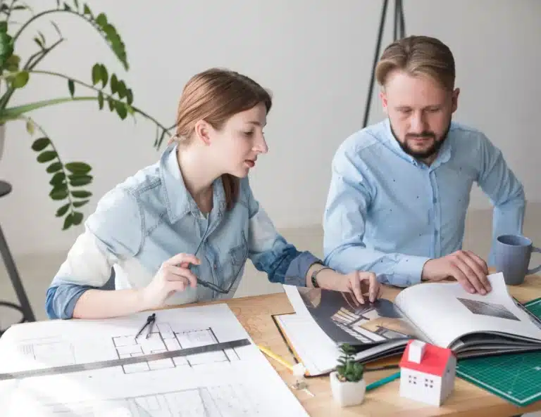 2 personnes travaillant dans un bureau sur des plans